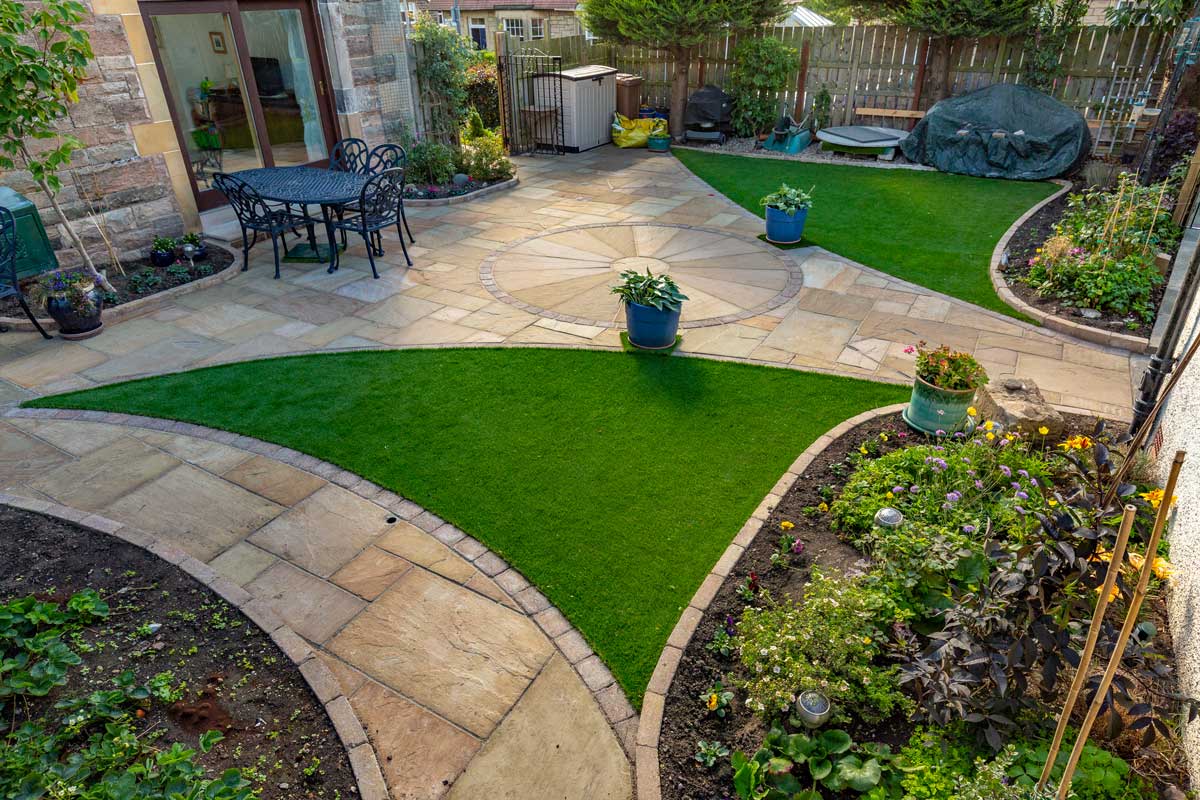Garden design, patio, paths, artificial grass & landscaping by Stow Construction & Landscaping in Morningside Grove, Edinburgh 2018 using Marshalls Fairstone Riven Harena Golden Sand, Marshalls Fairstone Riven Harena Golden Sand new circle, Marshalls Tegula Drivesett Harvest, Weatherpoint Buff 365, Marshalls Fairstone Sawn Vesuro bull-nosed step units, Namgrass, Marshalls Drivesett kerbs Harvest