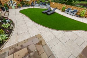 Patio, steps, artificial grass & landscaping by Stow Construction & Landscaping in Smithycroft, Hamilton 2018 using Marshalls Symphony Vitrified Buff, Drivesett Savannah Autumn, Fairstone Sawn Versuro bull-nosed steps Golden Sand, Fairstone walling Autumn Bronze, Evergreen Village Green 30mm artificial grass.